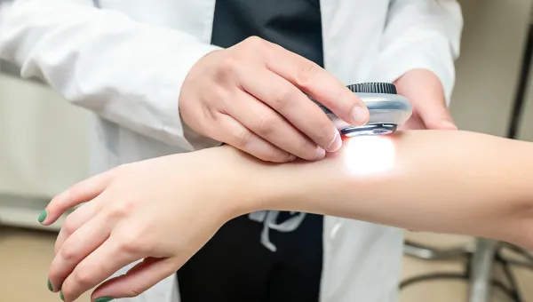 PA looking at the skin on a person arm with a magnifying device